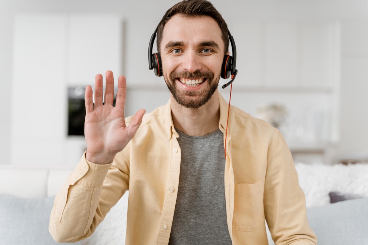 A man smiling on a video call, wearing a headset